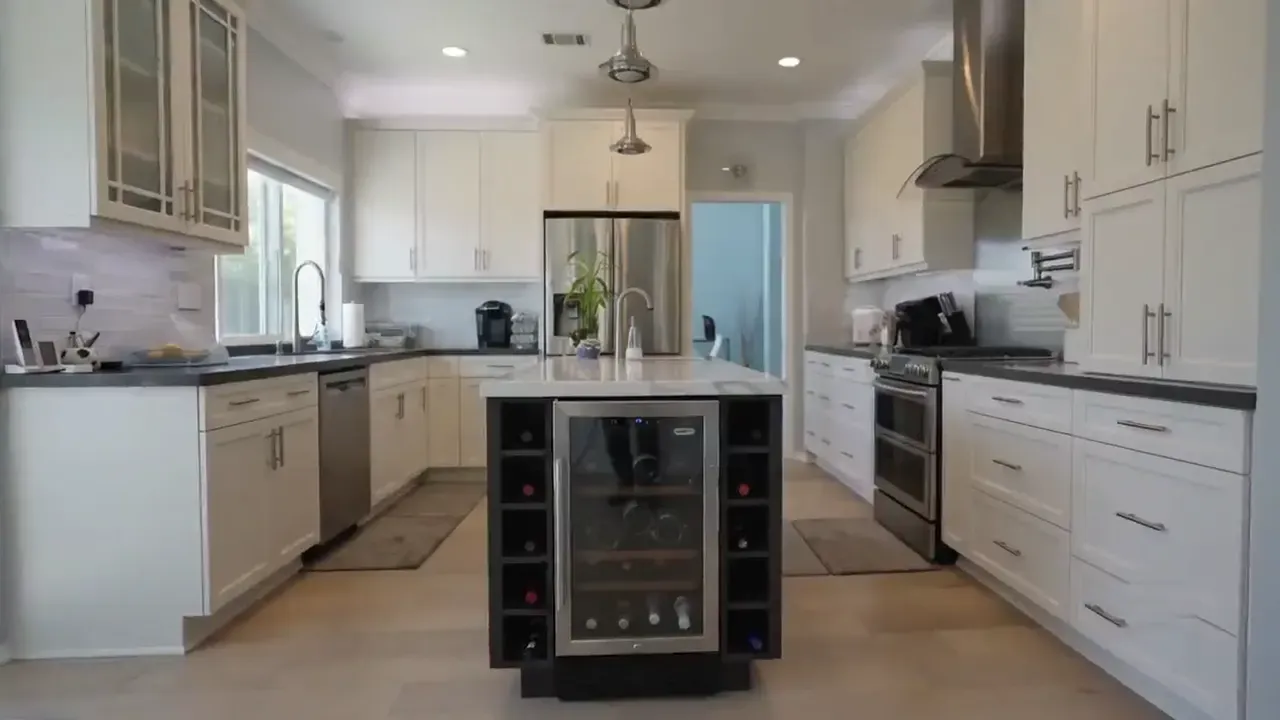 Galley kitchen with cream shaker cabinets, quartz island and a built-in wine fridge