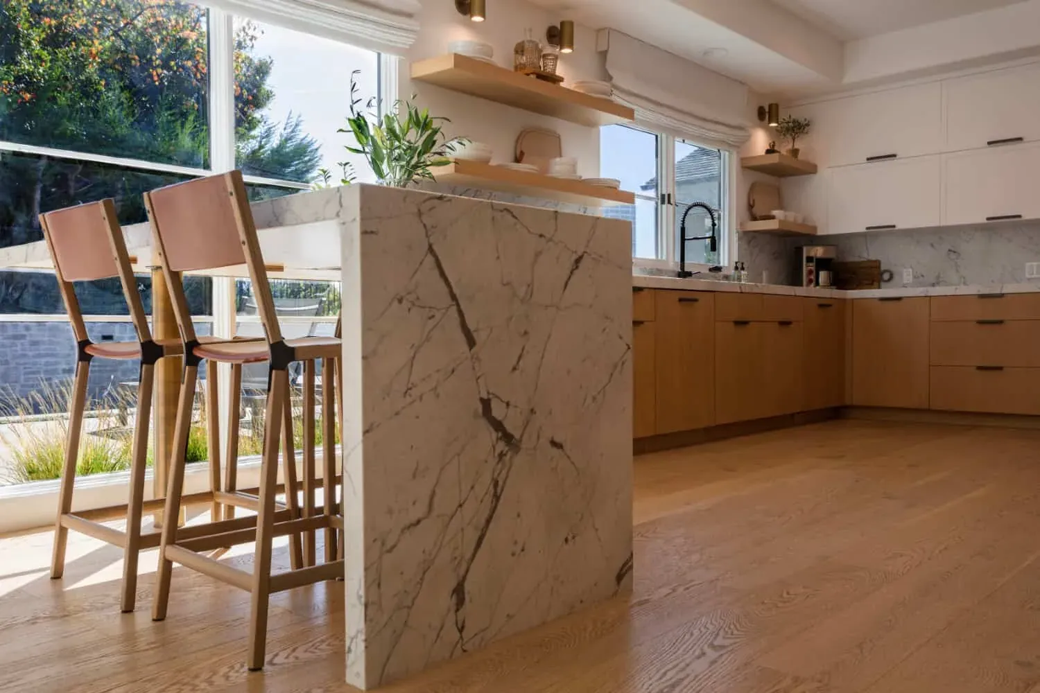 Marble waterfall island with bar stools and a window beyond