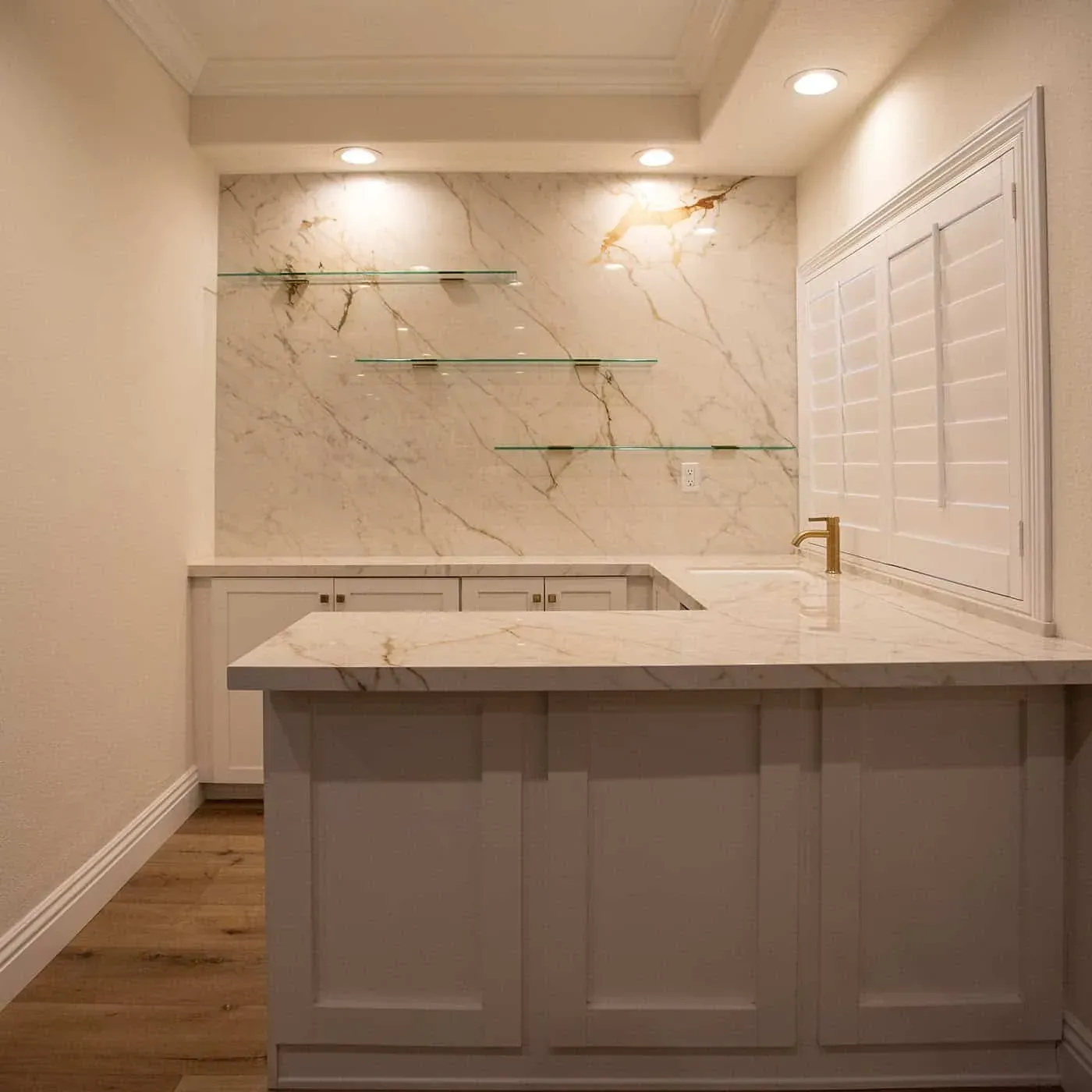 Bar area with glass shelves against a marble slab wall and a stone counter