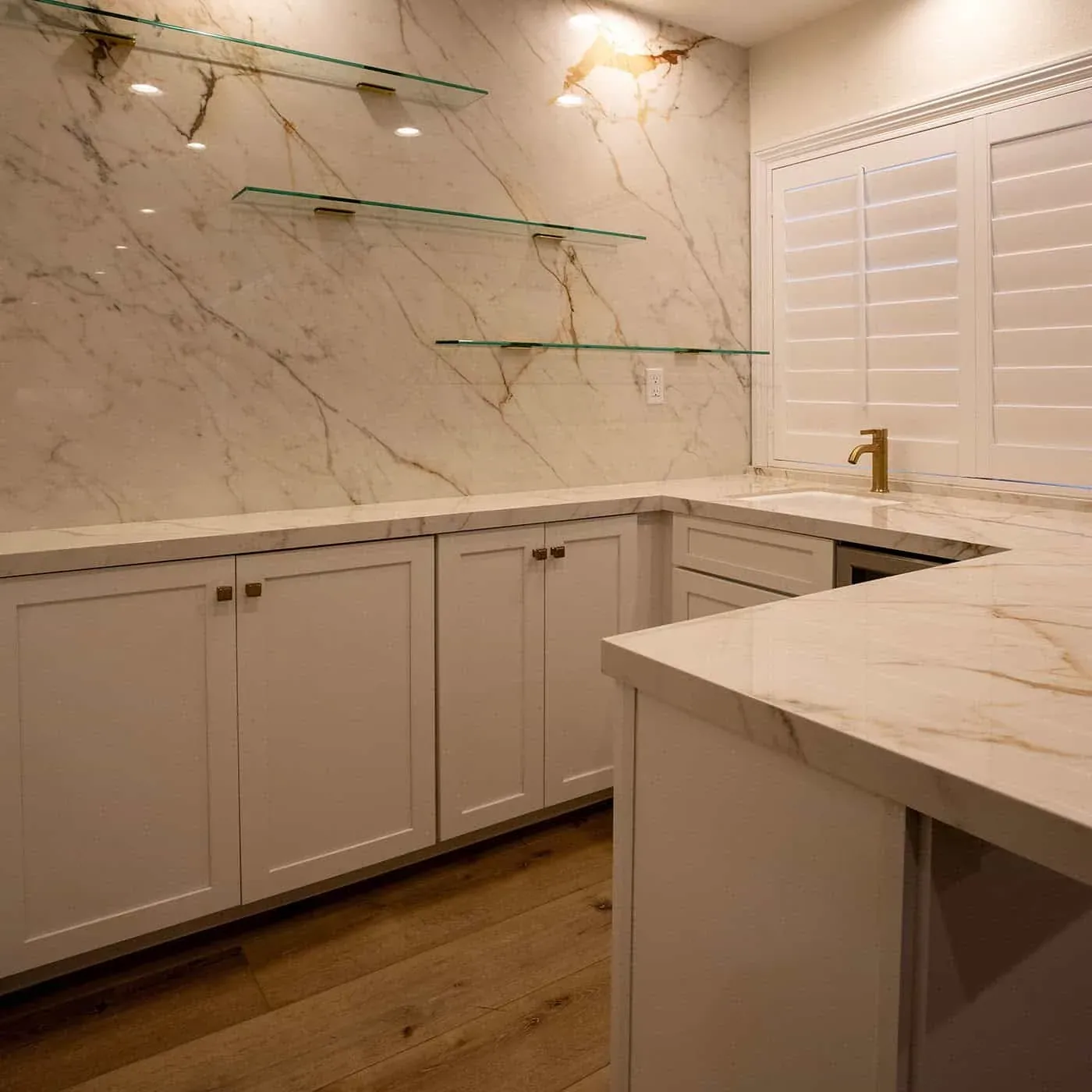 Bar run with glass shelving, a marble counter and a beverage cooler