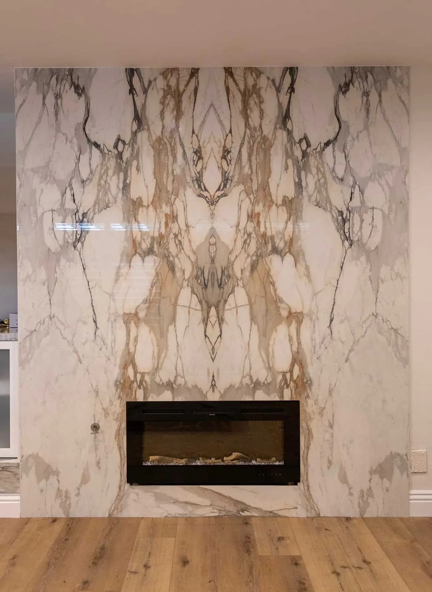 Book-matched marble slab wall rising above a fireplace