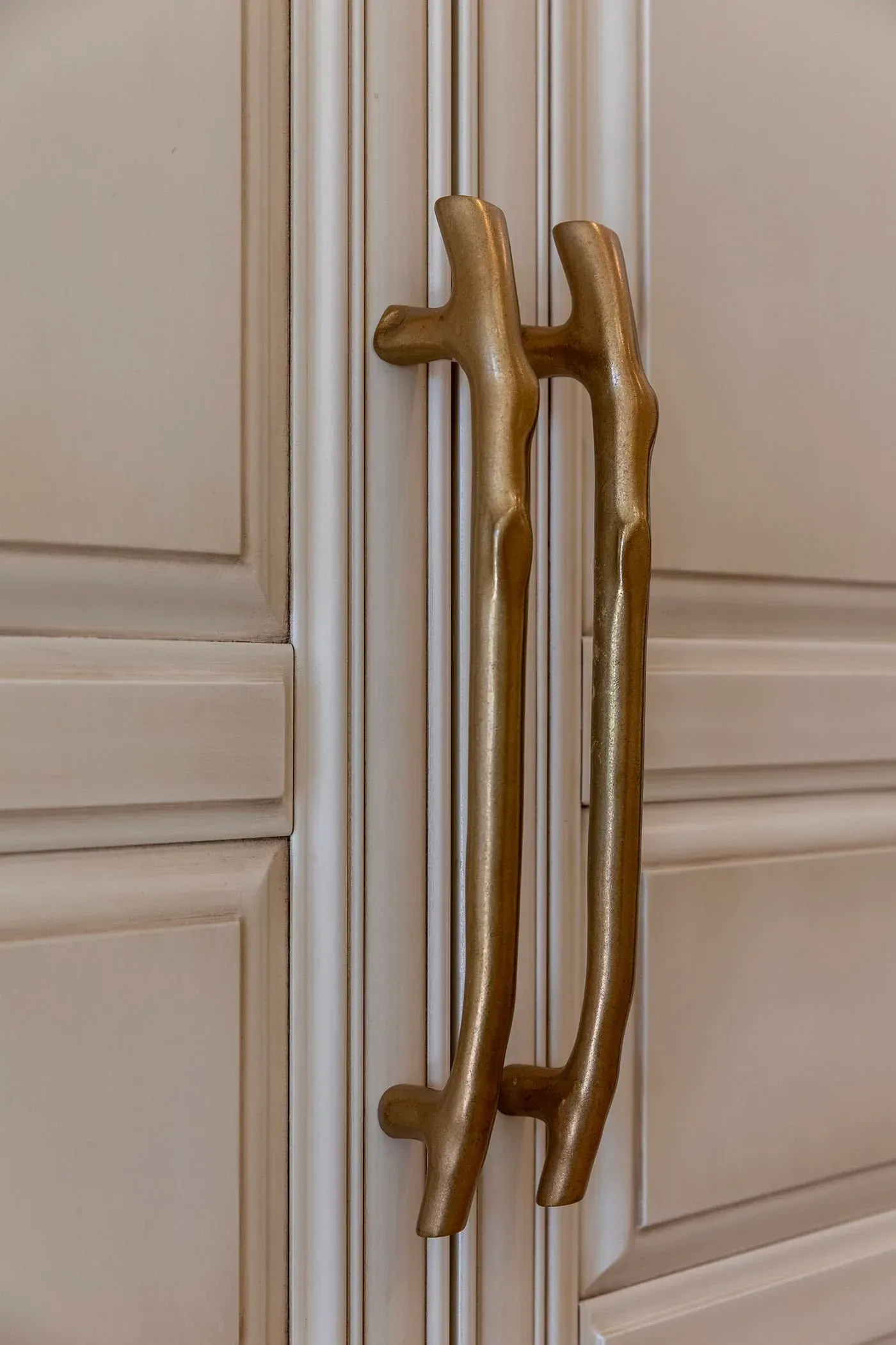 Brass appliance pulls on a panelled cream cabinet front
