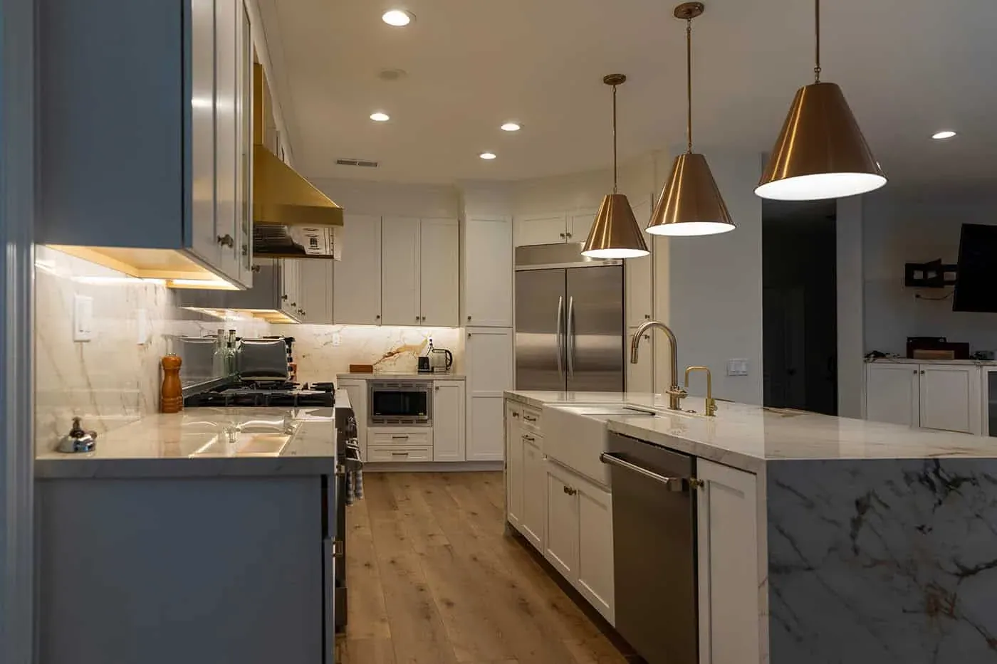 Yorba Linda kitchen with a brass hood above a stainless range, a marble backsplash and pendants