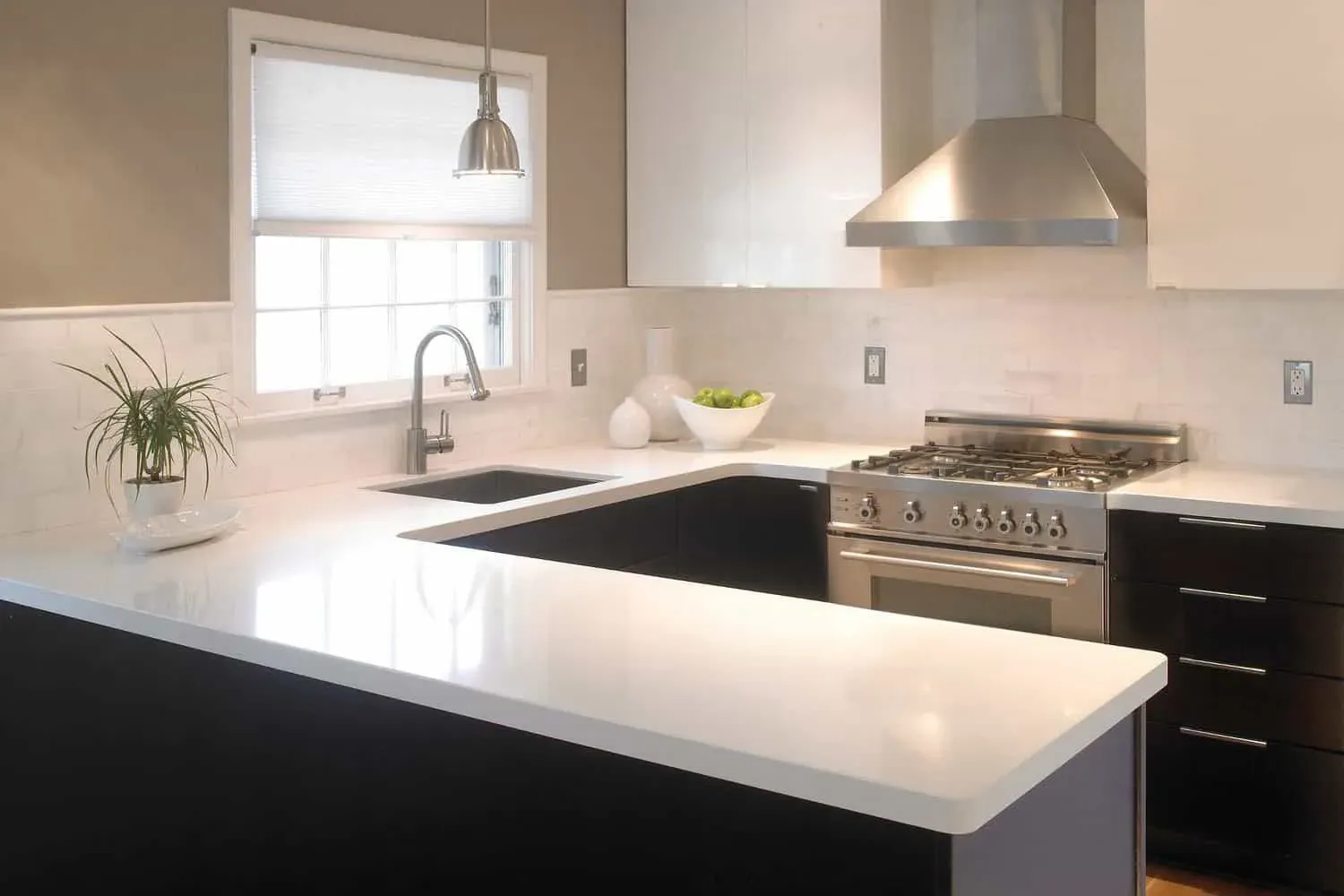 Cambria photograph of its Whitehall quartz design on a kitchen peninsula with dark base cabinets and a stainless range, not a Kitchen Cabinets and Beyond project