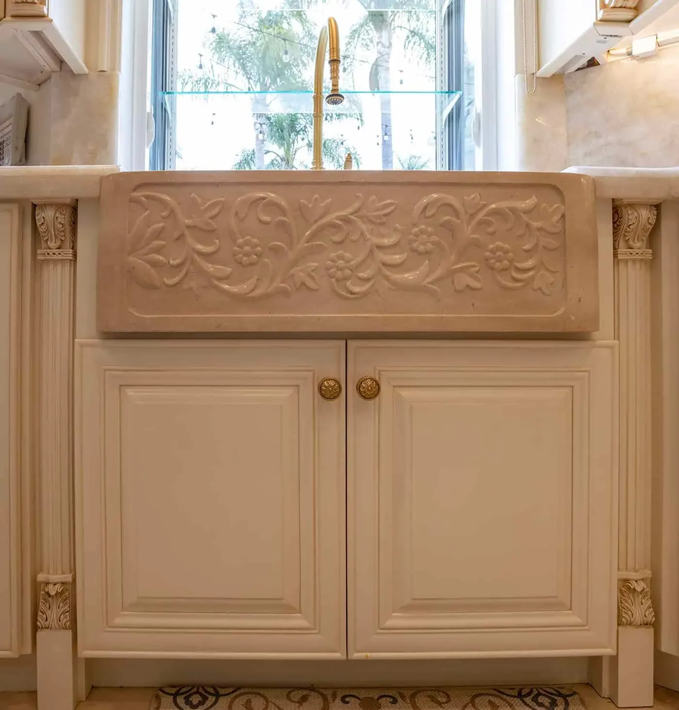 Carved floral relief panel above a pair of cream cabinet doors with round brass knobs