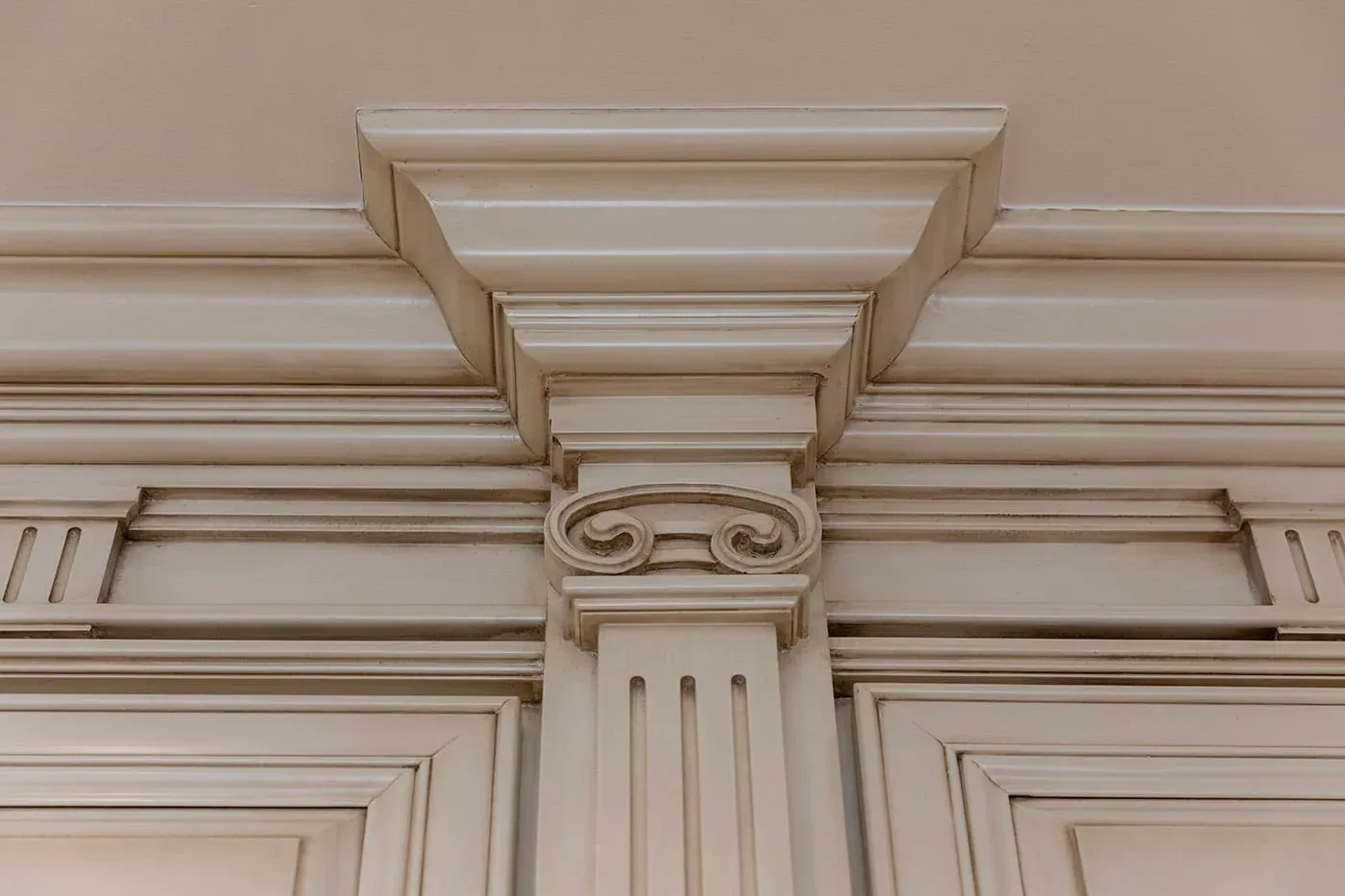 Carved capital on a fluted pilaster in cream cabinetry