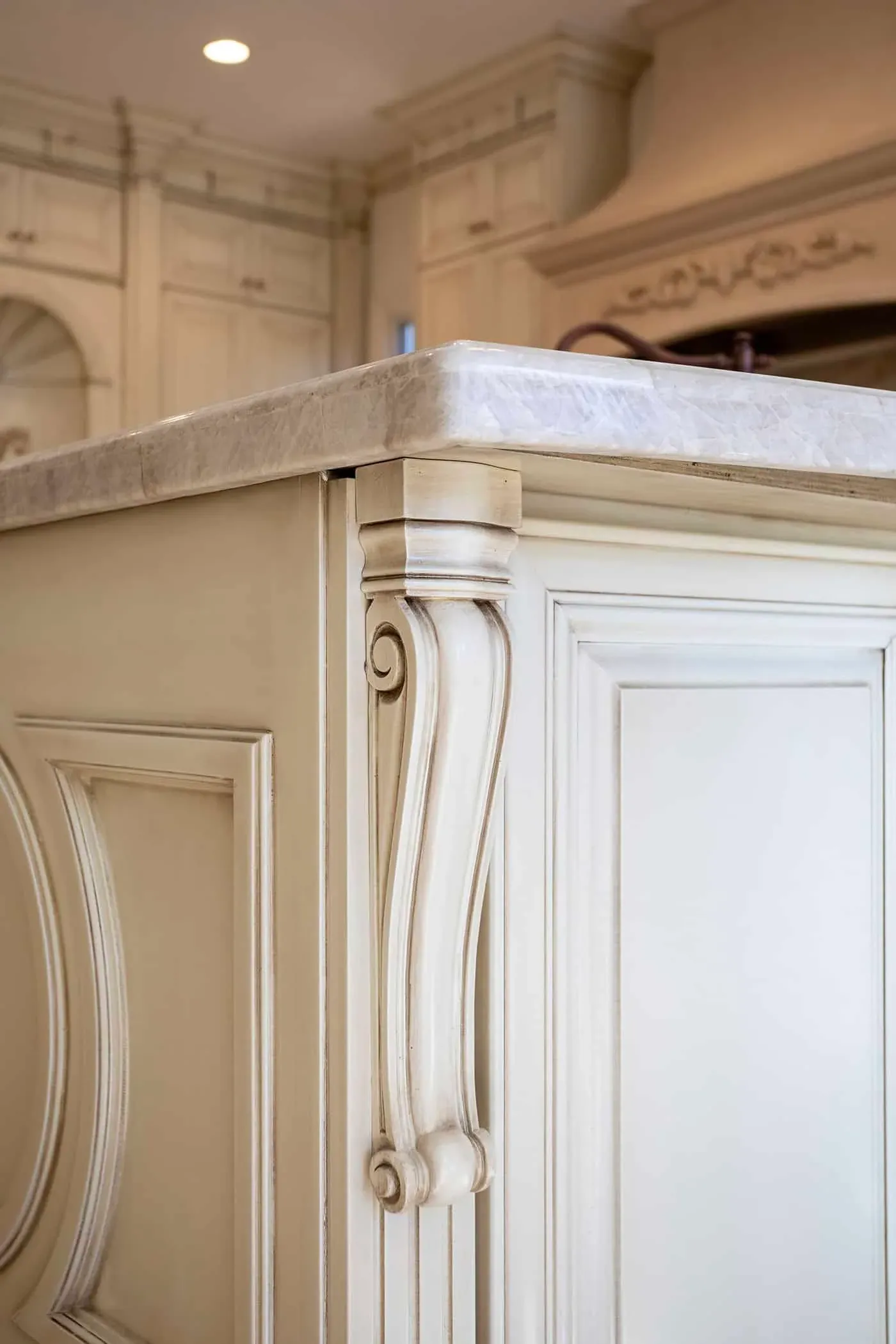 Carved corbel on a cream island end panel beneath a stone top