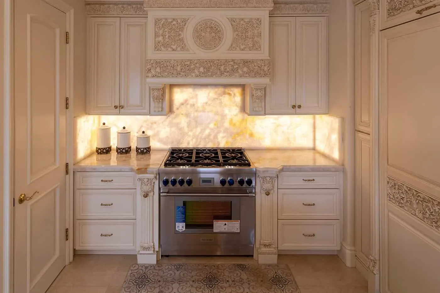 Laguna Hills kitchen with carved cream cabinetry around a professional range and backlit onyx