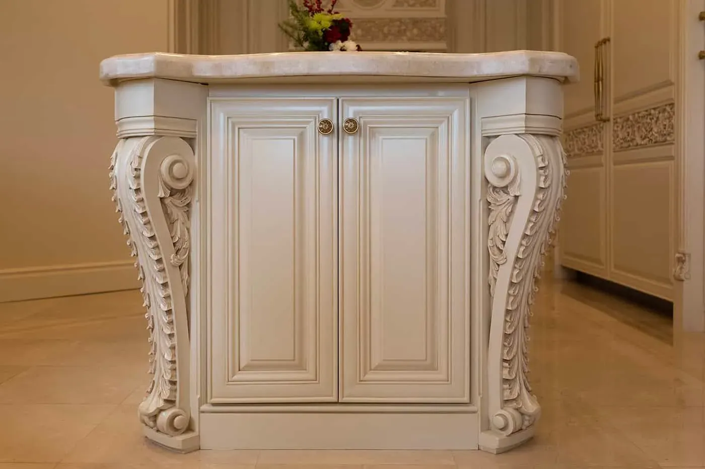 Cream kitchen island with carved scrolled corbels at each end under a marble top