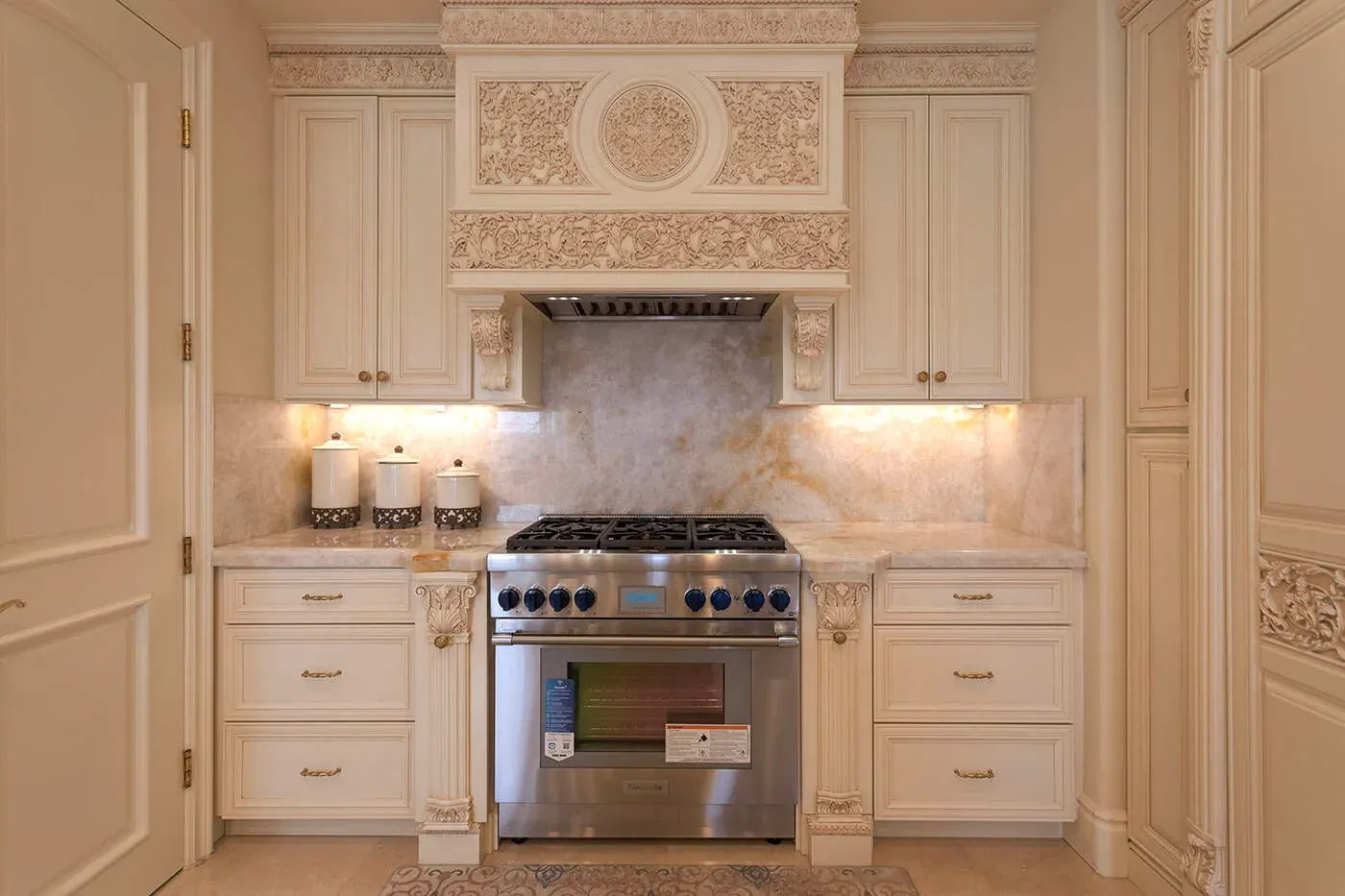 Carved hood surround with a medallion above a stainless professional range