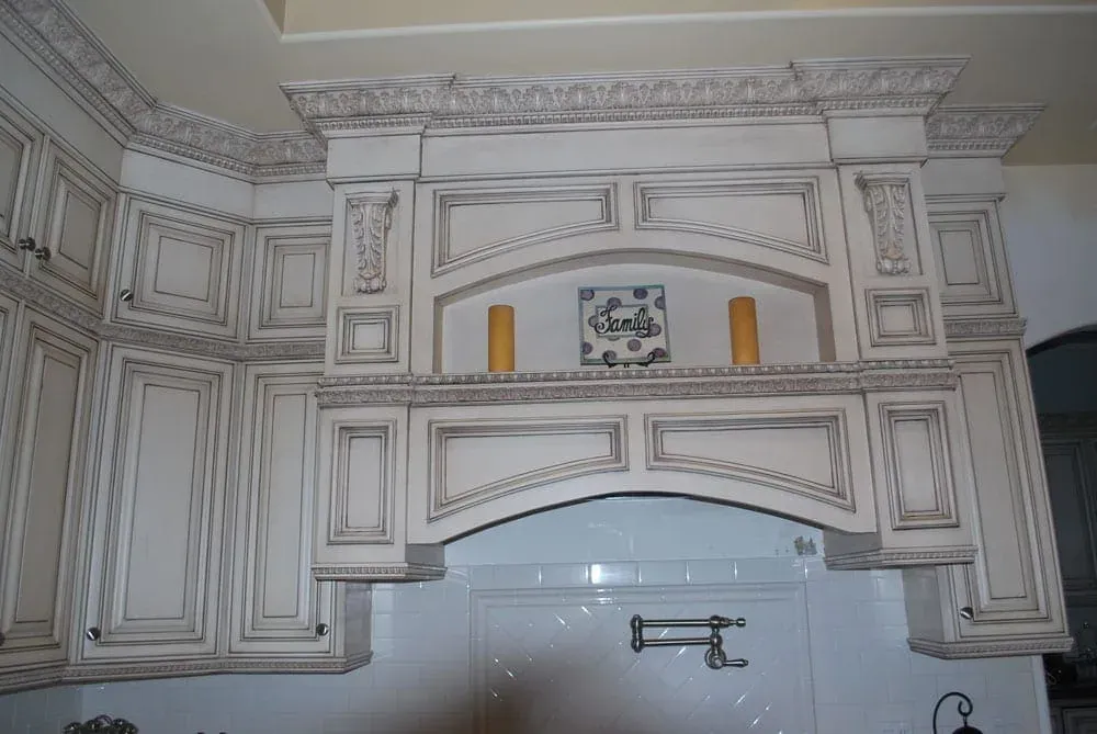 Carved hood surround over a tiled niche above the range