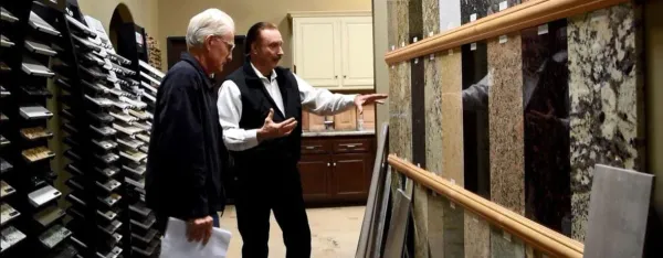 Kitchen designer showing a client granite slab samples on the showroom wall beside door sample racks