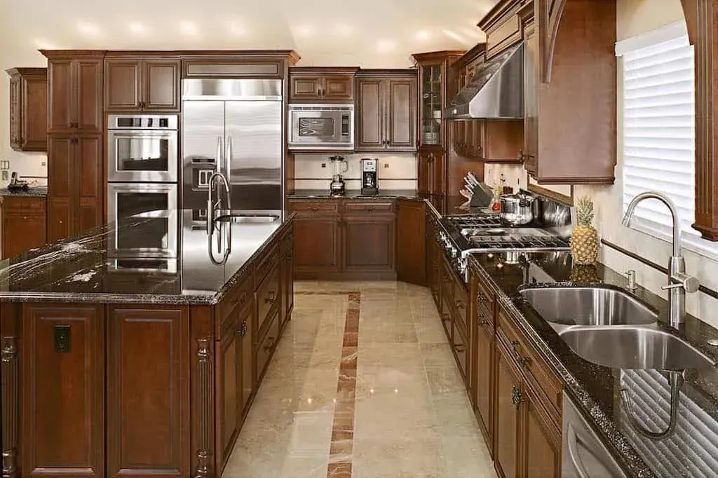 Cherry kitchen galley with granite counters, double wall ovens and a stainless refrigerator
