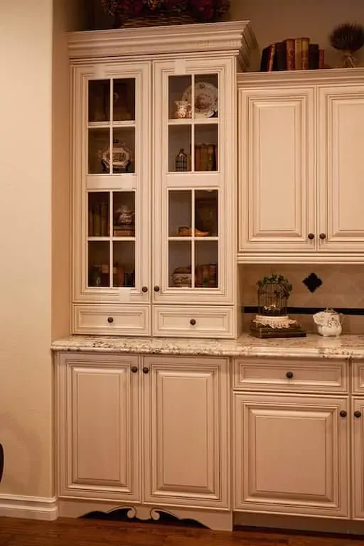 Cream glass-front cabinetry above granite counters with display shelving