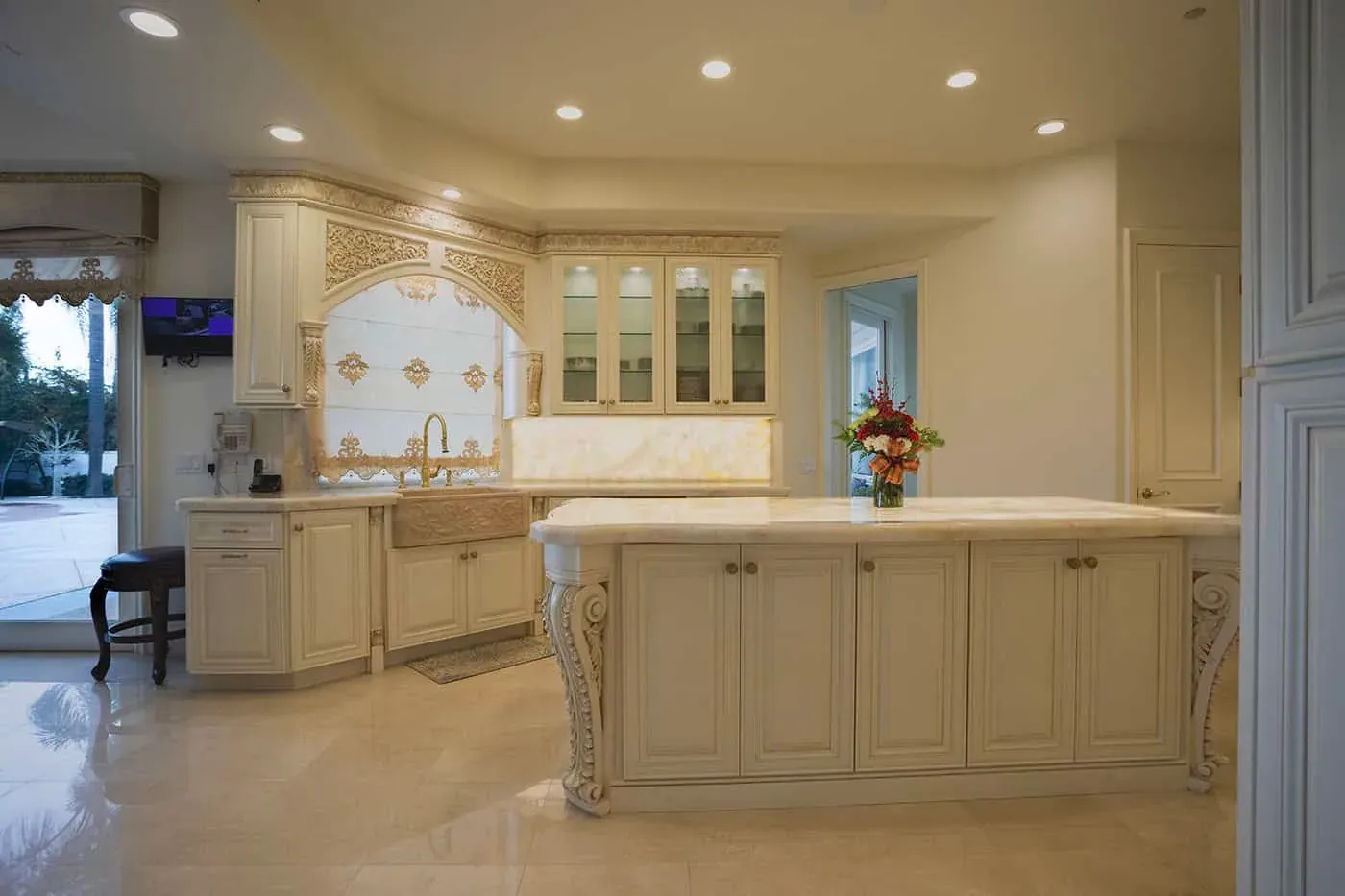 Laguna Hills kitchen with a carved island, a farmhouse sink and glass-front cabinets