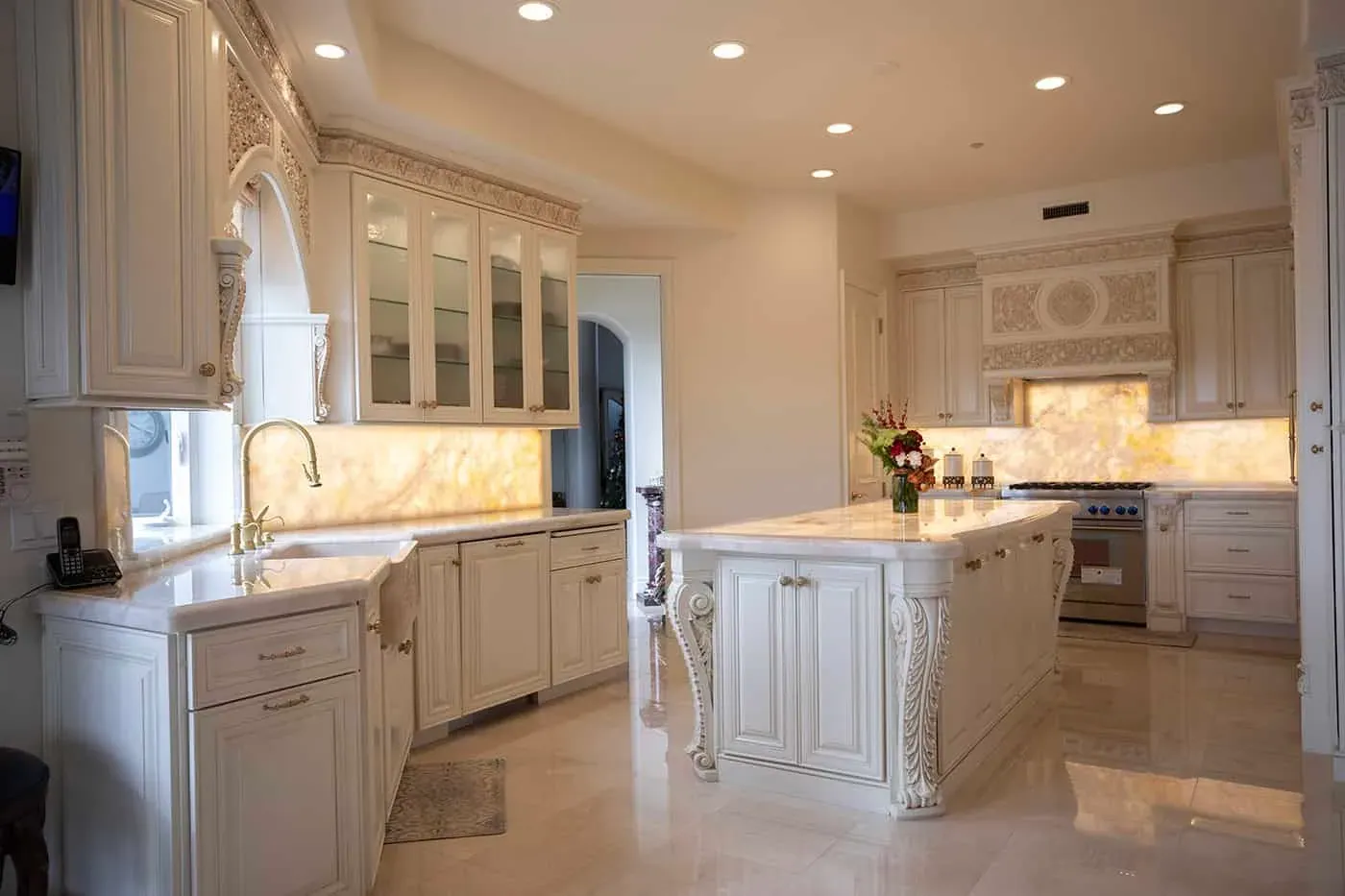 Cream kitchen with a carved island, glass-front cabinets and an onyx counter