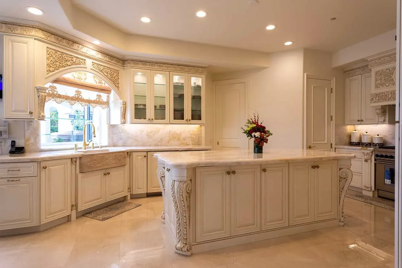 Cream kitchen with a farmhouse sink under the window and a carved island