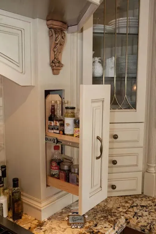 Narrow pull-out spice cabinet built into cream cabinetry