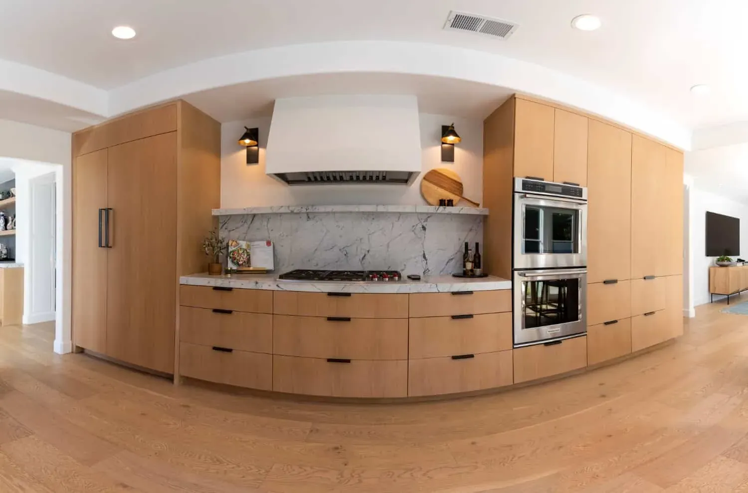 Curved plaster hood above a cooktop against a full-height marble backsplash