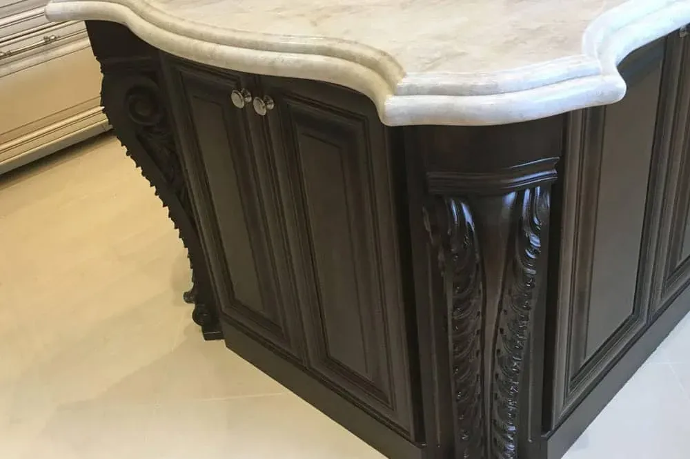 Carved corbel detail on an espresso stained custom cabinet end panel under a stone countertop