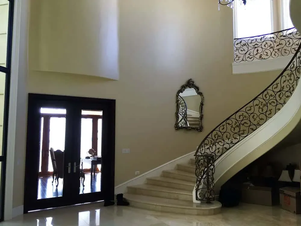 Entry hall with a curved iron staircase and dark double doors