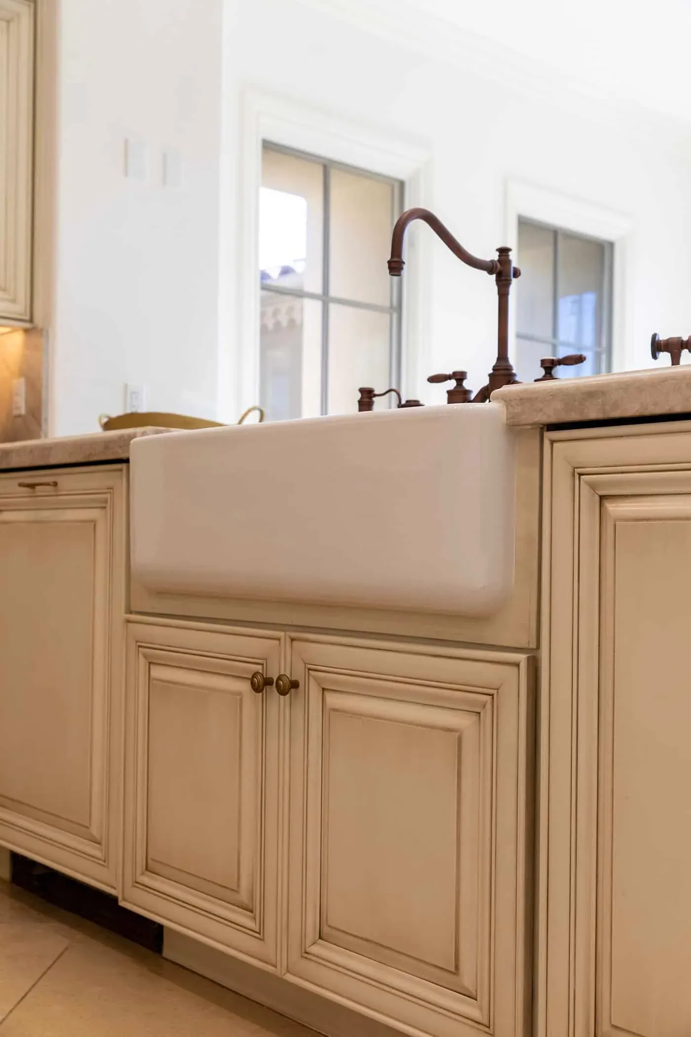 Newport Beach kitchen with a farmhouse apron sink and a bronze bridge tap in cream cabinetry