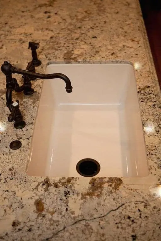 Farmhouse sink with a bronze tap set in a granite counter