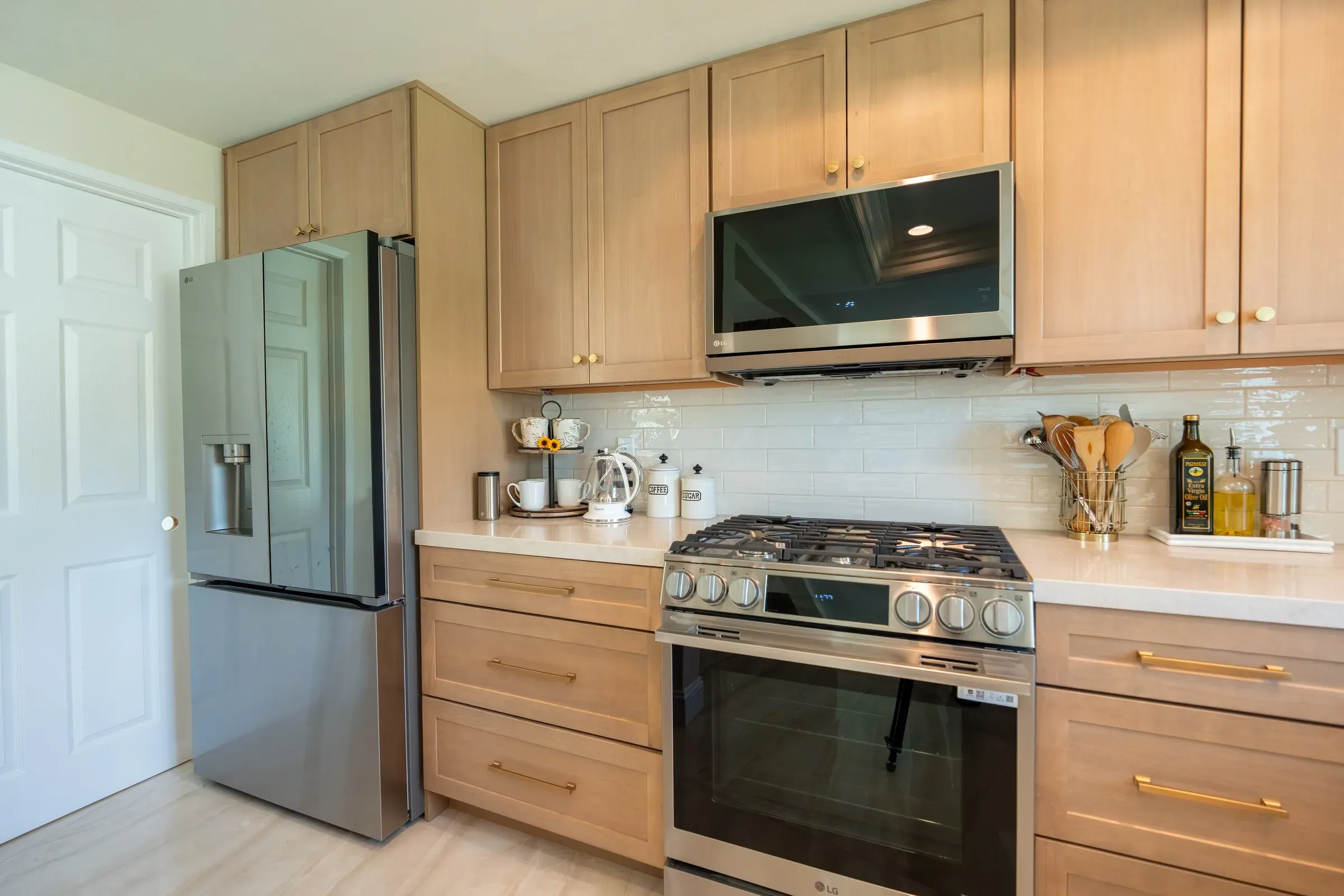 Light oak shaker kitchen with pale countertops, white subway tile, a stainless range and a French-door refrigerator