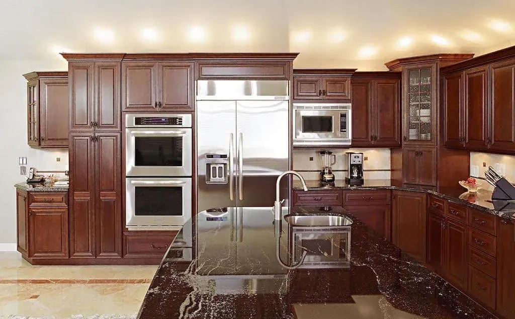 Fullerton kitchen with cherry cabinetry, double wall ovens and a dark granite island