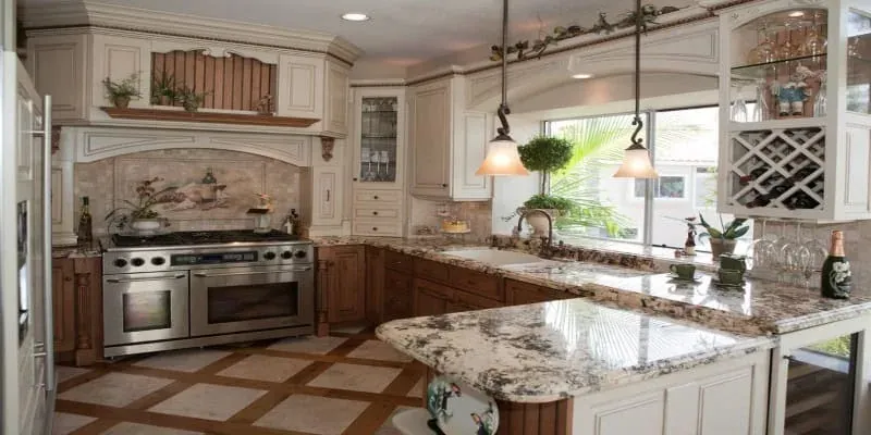 Cream raised-panel cabinets with granite countertops, a built-in wine rack and pendant lights over the peninsula