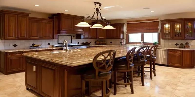 dark wood kitchen with large center island, bar stools, tile floor and ornate pendant chandelier