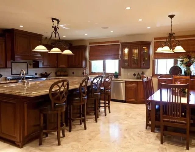 wood kitchen island with granite countertop, round-back bar stools and a nearby wood dining set