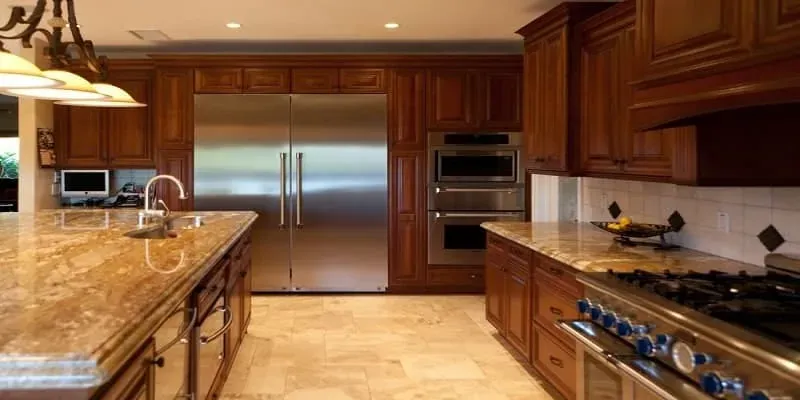 Cherry kitchen with a stainless refrigerator, a granite island and pendant lighting