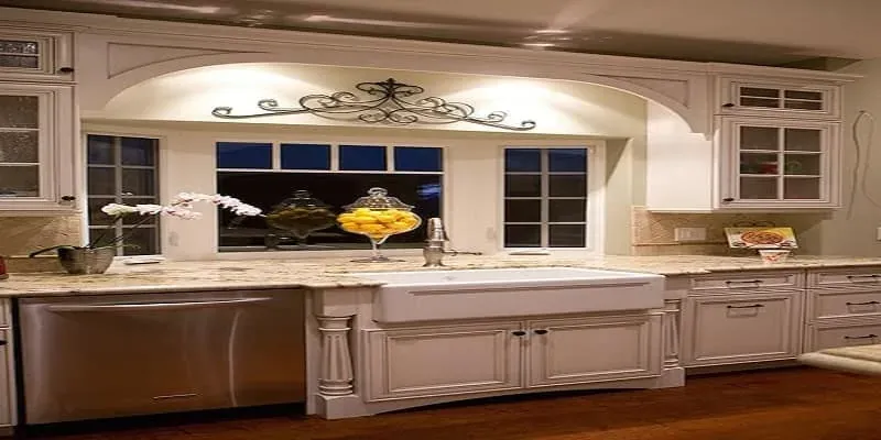 Cream kitchen with a farmhouse sink beneath an arched valance and a window