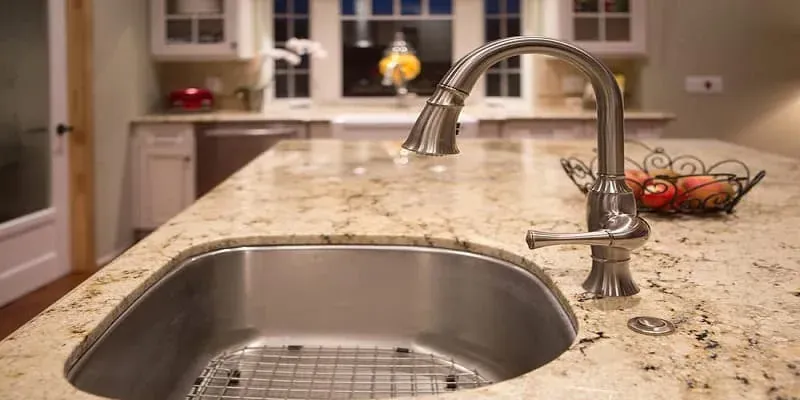 Granite countertop with a stainless undermount sink and a bronze pull-down faucet