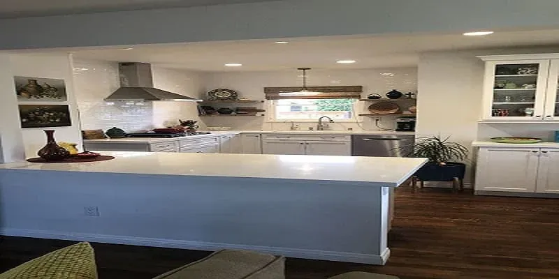 White kitchen with a quartz-topped island, a stainless hood and open shelving