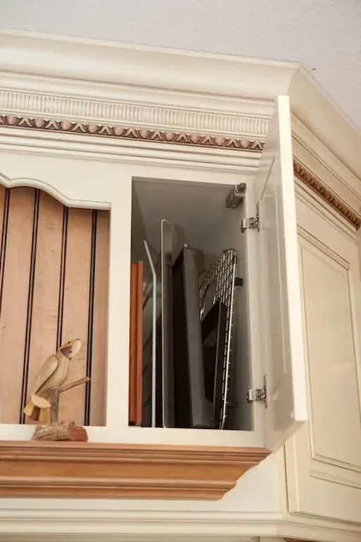 Open cabinet storing baking trays upright in slotted dividers