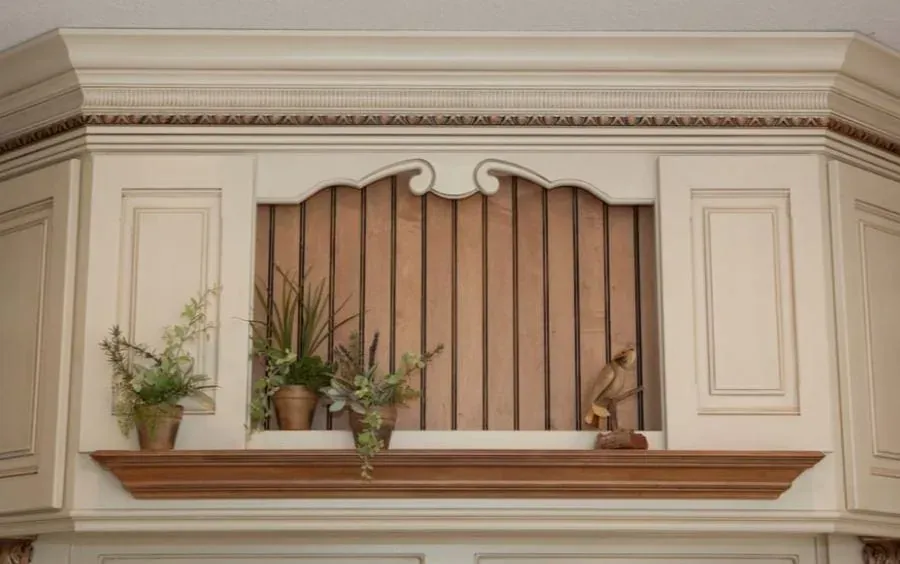 Cream cabinet display niche with a wood beadboard back, a wood shelf holding small potted plants and a figurine