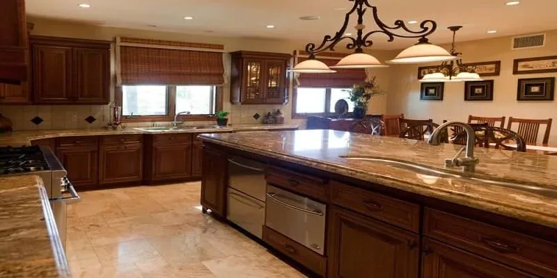 Wood-toned kitchen with a large island, pendant lighting, granite counters and a dining table nearby