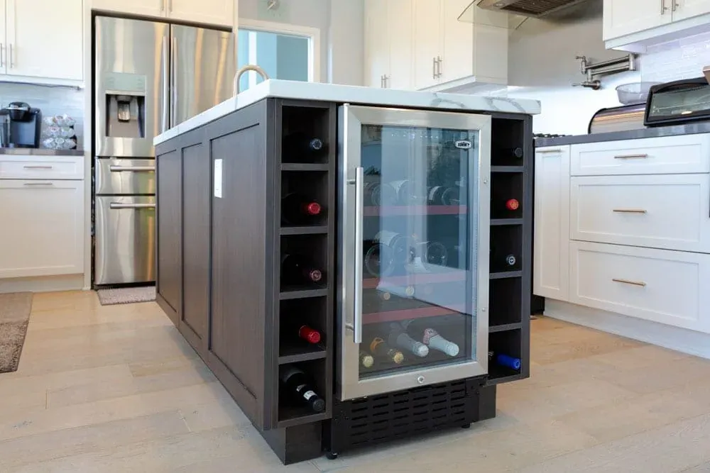 Dark island with a built-in wine rack and beverage cooler in a white kitchen