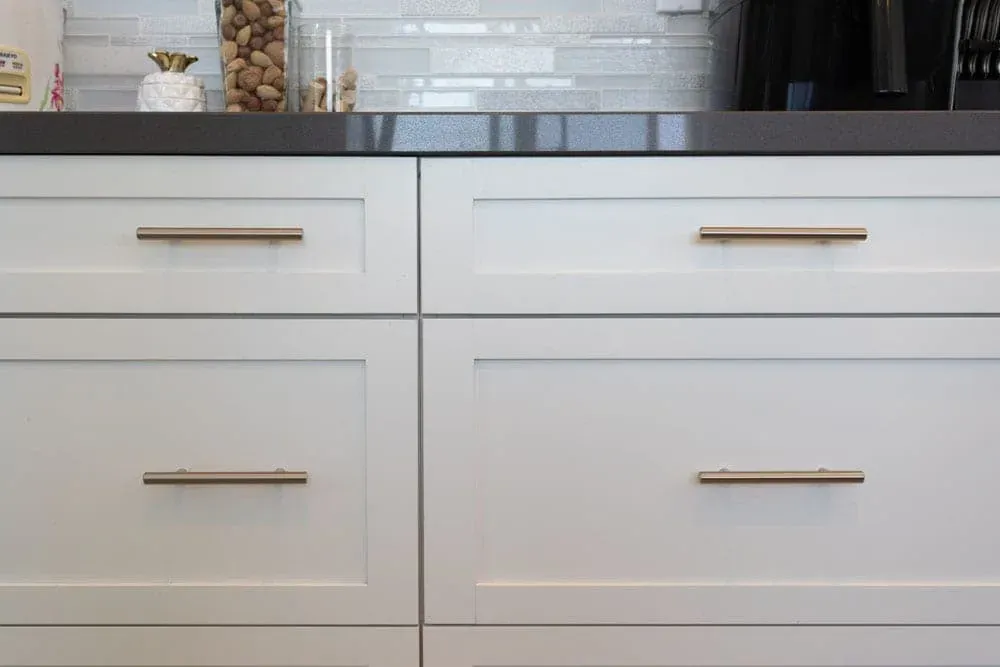 Mission Viejo kitchen drawers in white shaker with brass bar pulls under a dark counter