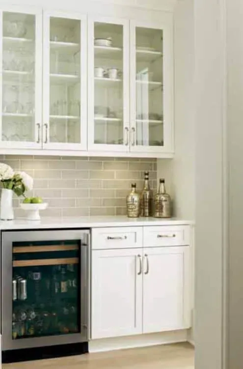 White cabinets with glass-front uppers above a built-in wine refrigerator