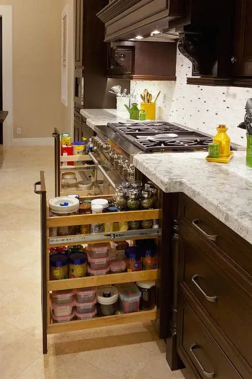 Dark cabinetry with a pull-out spice rack beside a gas cooktop