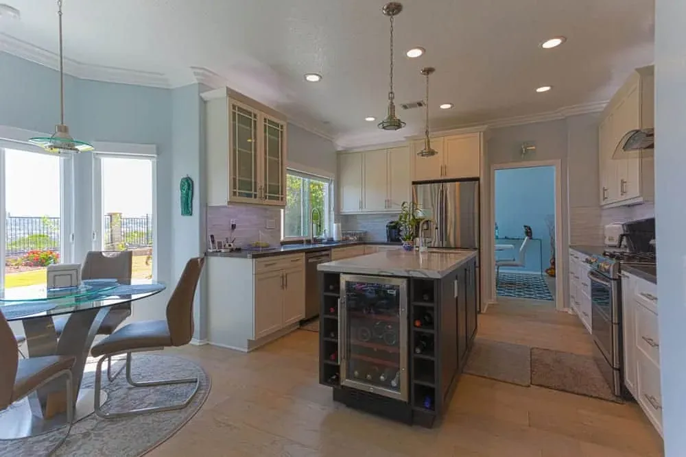 Pale tile floor running from a kitchen with a dark wine-cooler island through to the dining area
