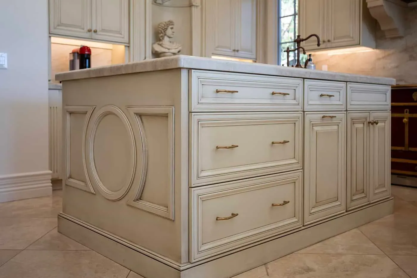 Cream kitchen island with oval applied panel detailing, drawer fronts and bronze hardware