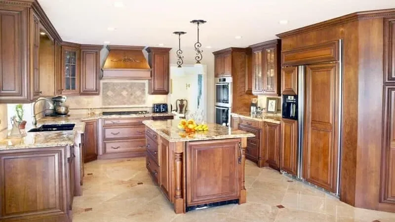 Medium-toned wood cabinets with a matching island, granite countertops and a built-in stainless refrigerator