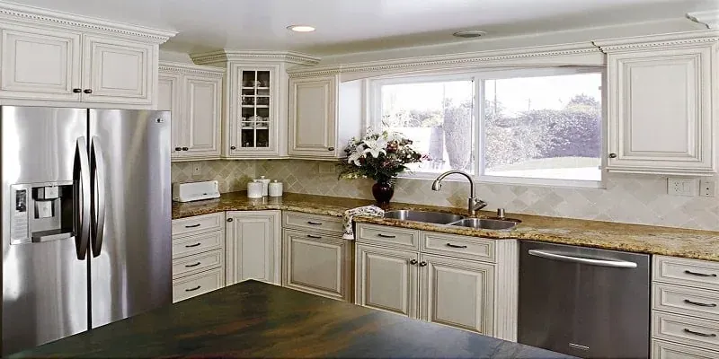 antique white cabinetry with granite countertops, a stainless French door refrigerator and a corner window above the sink