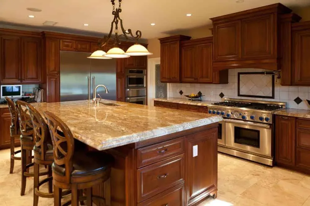 Cherry kitchen with a granite island, pendant lights and bar chairs