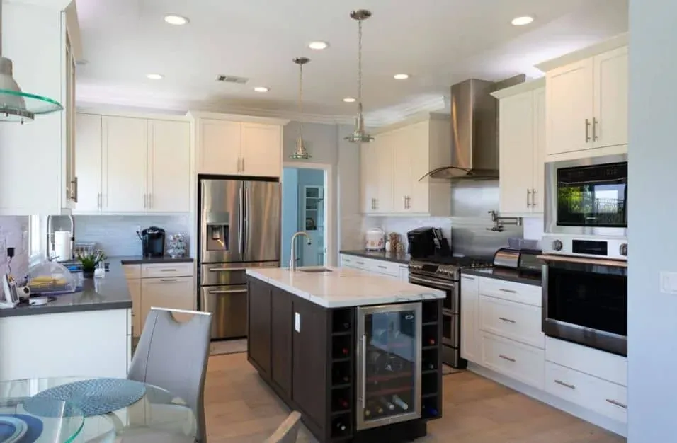 White cabinetry kitchen with a dark island, built-in wine cooler and stainless steel appliances