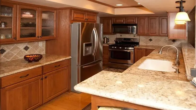 Cherry cabinetry kitchen with granite countertops, a stainless refrigerator and matching wall oven
